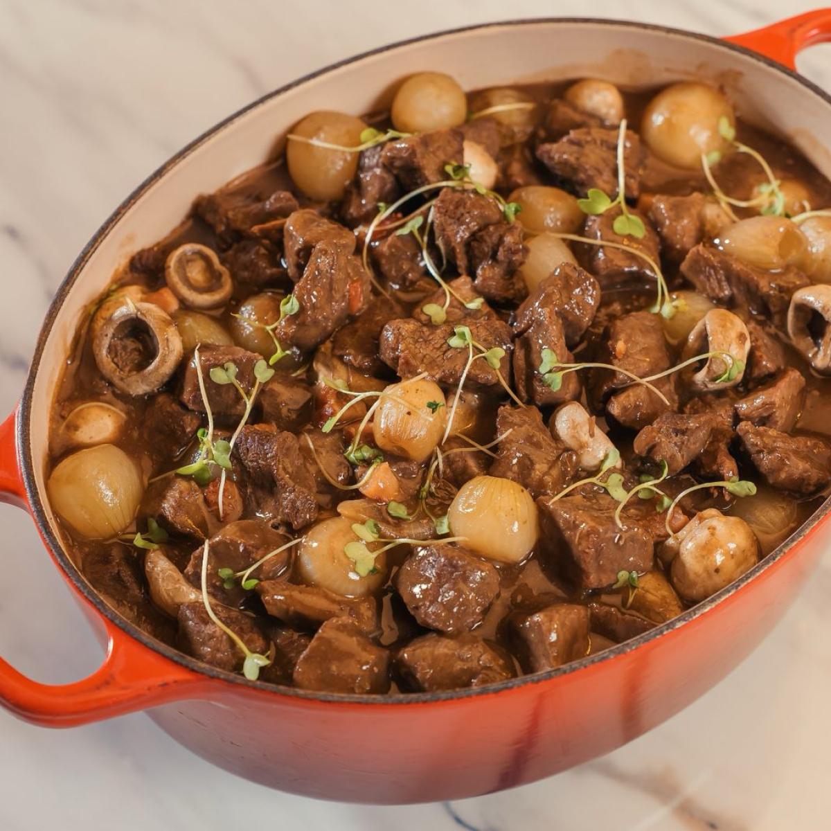 Panela de ferro com ensopado de carne, cebolas pérola e cogumelos